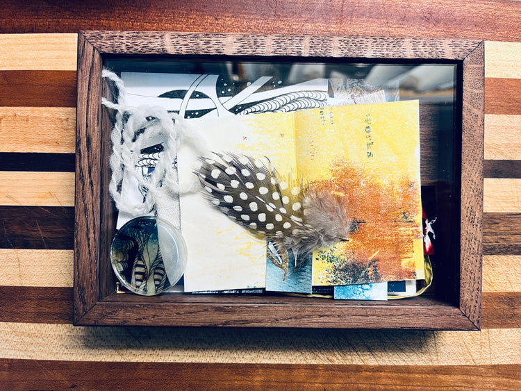 A wooden box with a clear sliding lid displays an eclectic mix of tiny art forms, including pen and ink drawings, monoprints, book-forms, photographs depicting Anet's travels and hand-knits, plus leaves, feathers, hand-spun yarn and hand-made cordage.