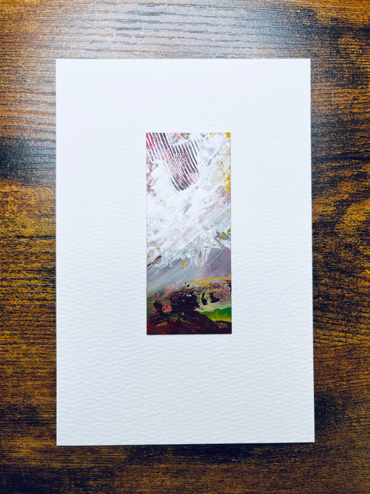 Original artwork by Anet Skillin. This miniature abstract landscape painting is painted on recycled packaging, in grey, yellow ochre, green, and red colors; mounted on 4x6-inch paper and photographed against a wooden table.