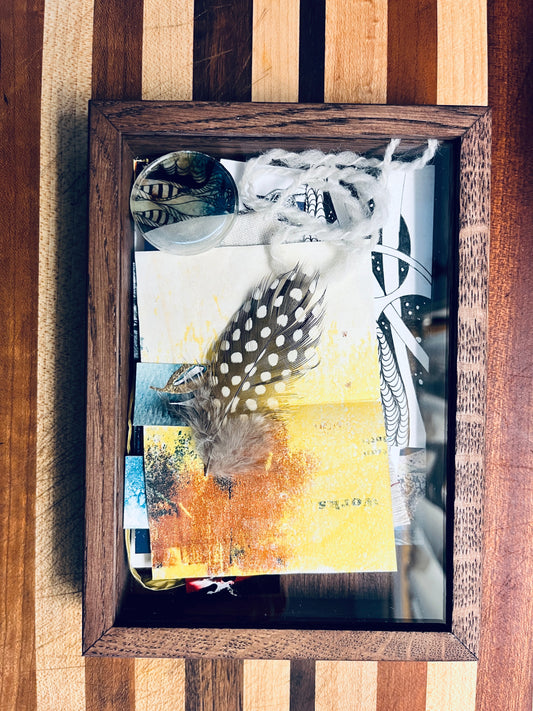 A wooden box with a clear sliding lid displays an eclectic mix of tiny art forms, including pen and ink drawings, monoprints, book-forms, photographs depicting Anet's travels and hand-knits, plus leaves, feathers, hand-spun yarn and hand-made cordage.