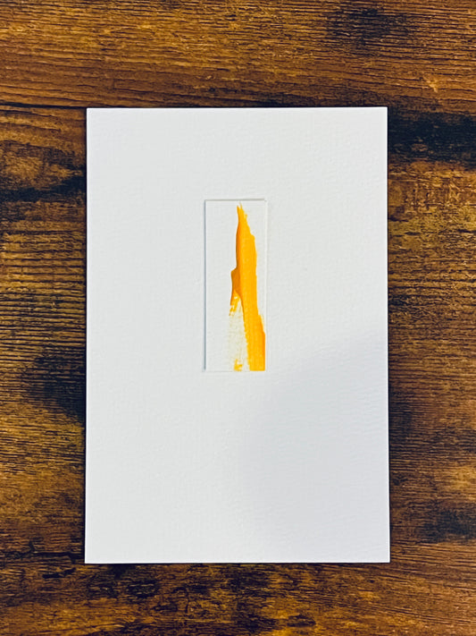 Original miniature abstract painting featuring yellow ochre acrylic paint on textured cold press watercolor paper, mounted on 4x6-inch watercolor paper in portrait orientation and photographed on a wooden table.