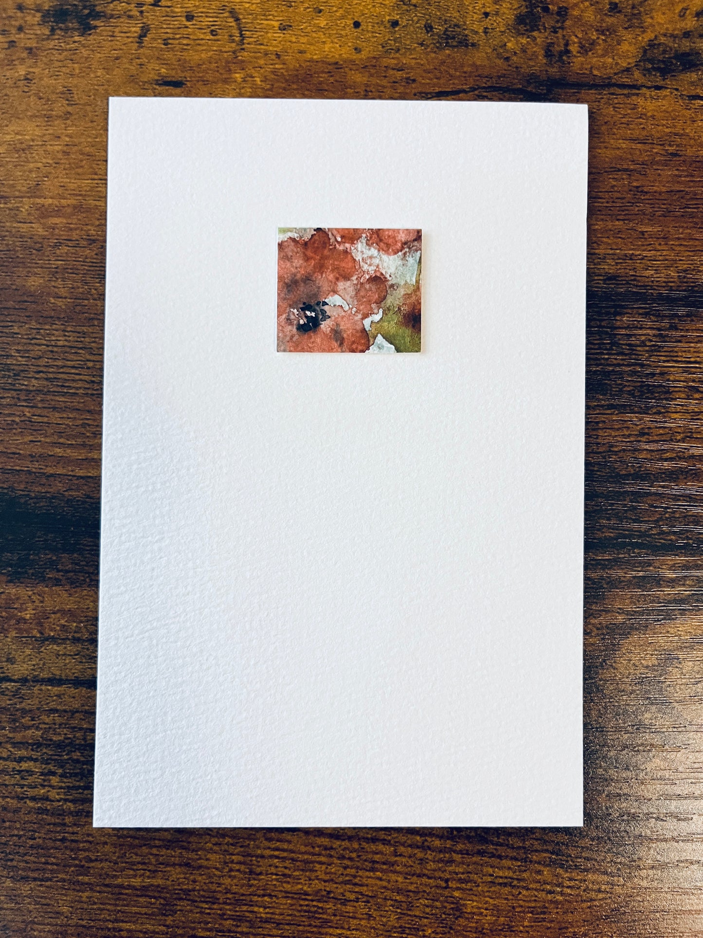 Original artwork by Anet Skillin. This miniature abstract floral painting features a poppy. Painted on textured cold-press watercolor paper, in orange-red, yellow-green, pale blue and black colors; mounted on 4x6-inch paper and photographed against a wooden table.